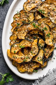 an overhead shot of baked eggplant chips on a white plate with parsley