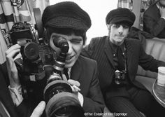 black and white photograph of two men taking pictures with their cameras in front of them