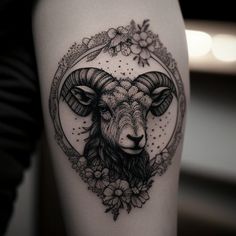 a ram tattoo on the thigh with flowers around it