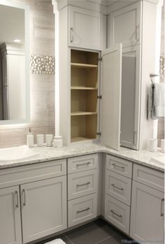 a bathroom with white cabinets and marble counter tops