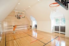 a young boy is playing basketball in an empty room with hard wood floors and white walls