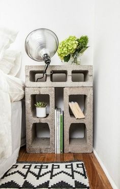 a book shelf made out of cinder blocks with books and plants on top, next to a lamp