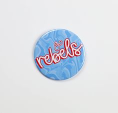 a button with the word reebels on it in red and blue swirls