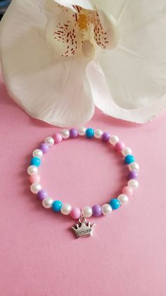 a bracelet with a crown charm on it next to a flower