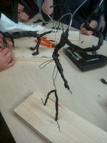 a group of people sitting around a wooden table with wires attached to the back of it