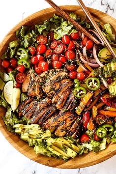 a bowl filled with meat, veggies and tomatoes