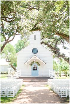 an outdoor wedding venue with white chairs and a blue door in front of the church