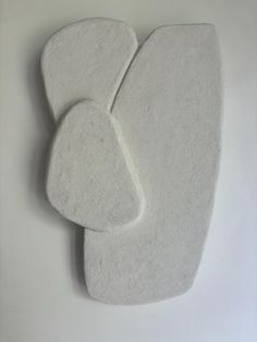 two white pieces of felt sitting on top of each other in front of a wall