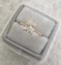 an engagement ring in a velvet box on top of a carpeted surface, with the diamond set at the center