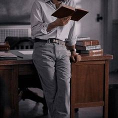 a man sitting at a desk reading a book