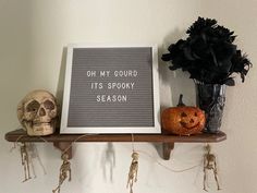 a sign that says oh my gourd it's spooky season next to two skulls and a vase with flowers