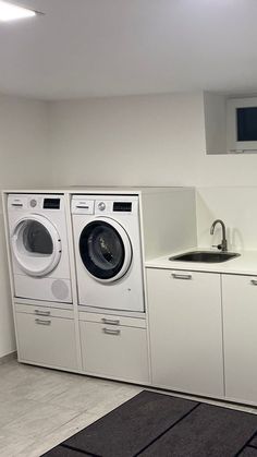 a washer and dryer in a small room with white cabinets on the wall