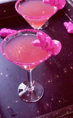 two glasses filled with pink liquid sitting on top of a black table next to each other