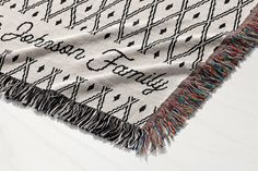 a black and white blanket with the word family printed on it, laying on top of a wooden floor