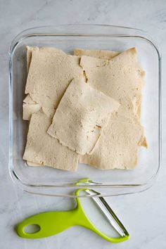 several pieces of pita bread in a glass dish next to a green spatula