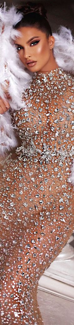 a woman with white feathers on her body posing for the camera, wearing a sparky dress