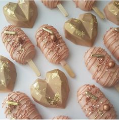 some pink and gold heart shaped lollipops are on a white table with gold pins