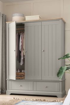 a grey armoire in a bedroom next to a window