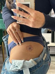 a woman is showing off her stomach with a flower tattoo on it's side