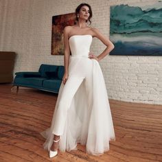 a woman in a white dress standing on a wooden floor