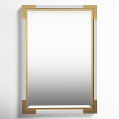 a mirror hanging on the wall next to a white wall with a gold trim around it