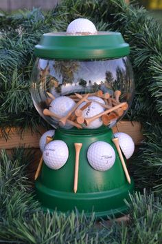 a snow globe filled with golf balls and tees sitting on top of evergreen branches