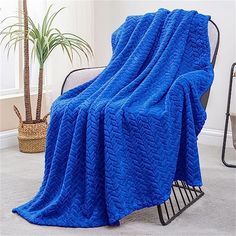 a blue blanket sitting on top of a chair next to a potted plant