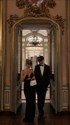 a man in a tuxedo standing next to a woman in a black dress