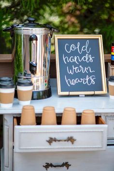 a sign that says cold hands warm hearts next to coffee cups and a crock pot