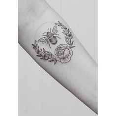 a black and white photo of a tattoo with flowers on the arm that has two bees in it