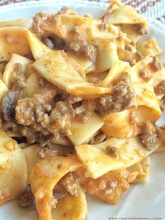 a white plate topped with pasta covered in meat and cheese sauce on top of a table