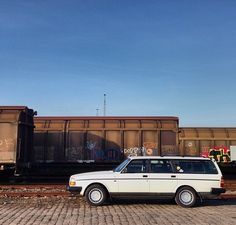 a white station wagon parked in front of train cars