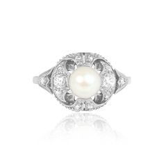 a white pearl and diamond ring with an intricate design on the front, set in 18k white gold