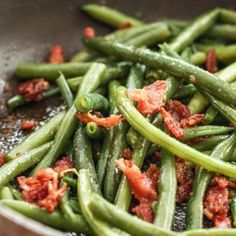 green beans and tomatoes cooking in a wok on the stove with some seasoning