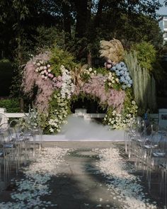 an outdoor ceremony setup with clear chairs and flowers