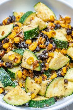 a white bowl filled with zucchini, corn and black bean salad on top of a table