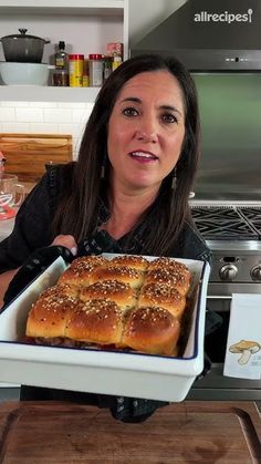 a woman holding up a tray of bread