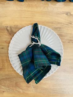 a white plate topped with a green and blue plaid napkin on top of a wooden table