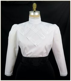 "Cotton/Poly. Color: White. Pima blend broadcloth fabric designed with raschel scalloped white lace trimmed design front. Button back stand up collar and full length gathered sleeves with white lace trim cuffs. Machine washable. Circa 1905-1910. Made in U.S.A. Sizes: SM, MED, LG & XLG. Blouses ordered by bust measurement, inches: BUST SIZES 32\" - 34\" SMALL 35\" - 39\" MEDIUM 40\" - 44\" LARGE 45\" - 49\" XLARGE Blouses ordered by bust measurement, centimeters: SMALL 81 cm - 86 cm MEDIUM 88 Fitted White Tops With Contrast Lace, Formal Fitted Blouse With Ruffled Collar, White Elegant Tops With Contrast Lace, Elegant White Tops With Contrast Lace, Fitted Blouse With Lace Trim For Workwear, White Stand Collar Tops For Daywear, Fitted Top With Lace Sleeves For Work, Elegant Stretch Blouse For Daywear, Classic Fitted Blouse With Peter Pan Collar