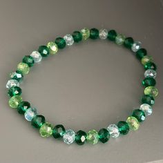 This is a beaded bracelet, made of 6mm acrylic faceted beads in the shades of emerald green, light green, and glass. The bracelet is stretchy (no clasp) with an approximate circumference of 7 inches.  Thanks for visiting my shop. Please message me if you have any questions! Adjustable Green Crystal Bracelet With 8mm Beads, Green Stretch Bracelet With Faceted Round Beads, Faceted Green Beaded Bracelets For Gift, Faceted Green Beaded Bracelets As Gift, Gift Green Faceted Beaded Bracelets, Green Czech Glass Beaded Bracelets, Green Faceted Round Bead Bracelets, Green Crystal Bracelet With Round Beads And Adjustable Fit, Green Adjustable Crystal Bracelet With Round Beads