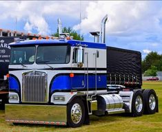 a large semi truck parked on top of a grass covered field