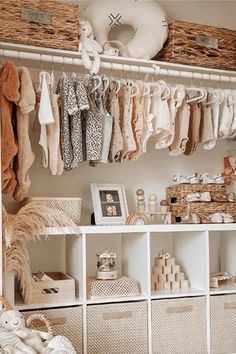 a closet filled with lots of baby clothes and baskets on top of it's shelves