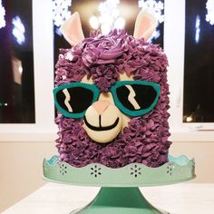 a cake decorated like a llama with sunglasses on it's head and flowers in the hair