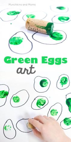 a child's hand is painting green eggs on a sheet of paper