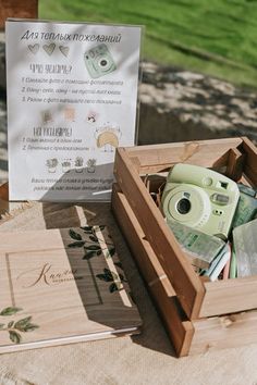 an open wooden box filled with assorted items sitting on top of a table next to a sign