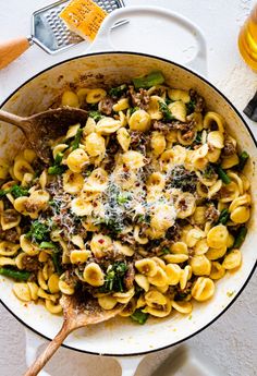 a skillet filled with pasta, meat and spinach on top of a table