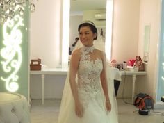 a woman standing in front of a mirror wearing a wedding dress