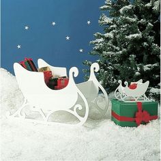 a sleigh with presents in the snow next to a christmas tree and gift box