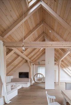 an open living room with wood floors and white furniture on the floor, along with wooden ceilinging