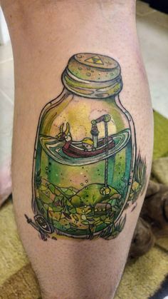 a woman's leg with a fish in a jar tattoo on it